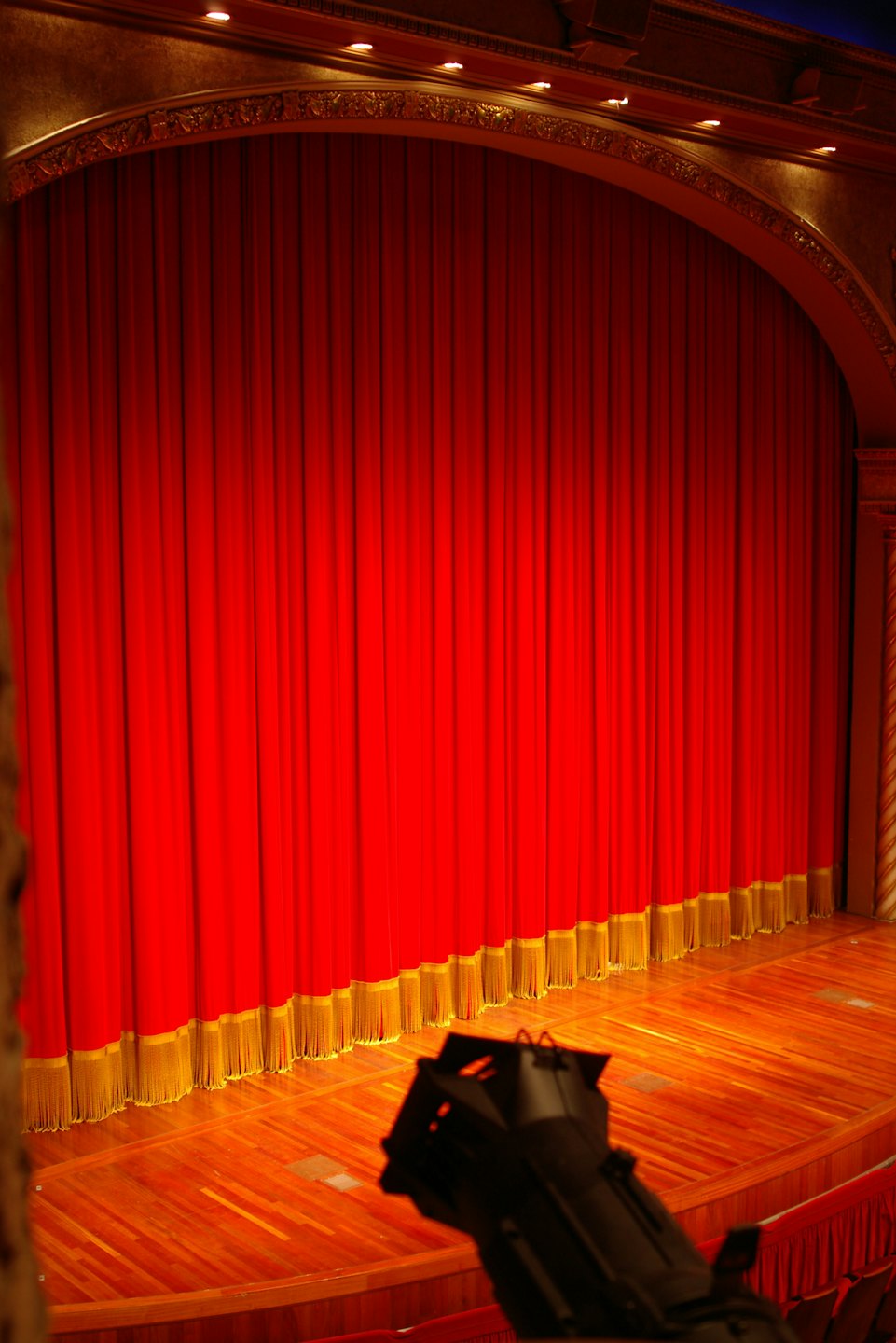 Leere Theaterbühne mit roten Vorhängen und goldenen Verzierungen.